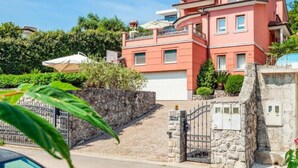 Una casa rosa de varios pisos con un muro de piedra y una puerta.