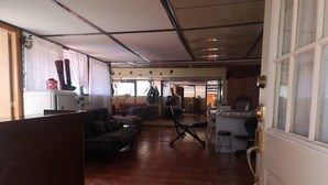 Un vaste espace de vie comprenant un grand canapé, une table basse et une table à manger avec des chaises. Il y a également un coin cuisine équipé d’un réfrigérateur et d’un évier.
