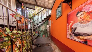 Un escalier avec des rampes en métal, des plantes en pot et une fresque murale.