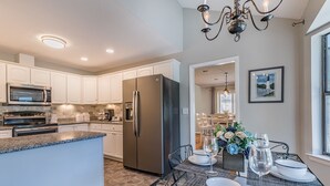 A modern kitchen with white cabinets, stainless steel appliances, and a dining area with a table set for two.