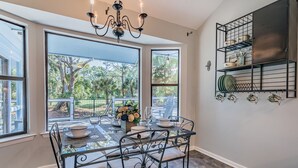 A dining area with a glass table, metal chairs, and a chandelier.