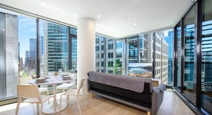 Enjoy a panoramic view of the city and ocean from this stylish living space with a round dining table and comfortable seating.