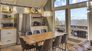 A modern kitchen with a dining area, large windows, and a ceiling fan. - Boho Chalet w/ Mountain Views (Beech Mountain)
