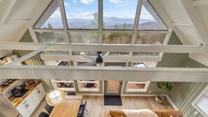 A spacious loft-style room with a high ceiling, a dining area, and a cozy seating area. - Boho Chalet w/ Mountain Views (Beech Mountain)