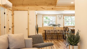 Una habitación acogedora con techo de madera, un sofá, una mesa de comedor con sillas y una planta en maceta.