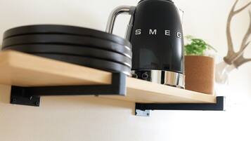 Una repisa en la cocina con tazas de café negro, una cafetera negra y una planta en maceta.