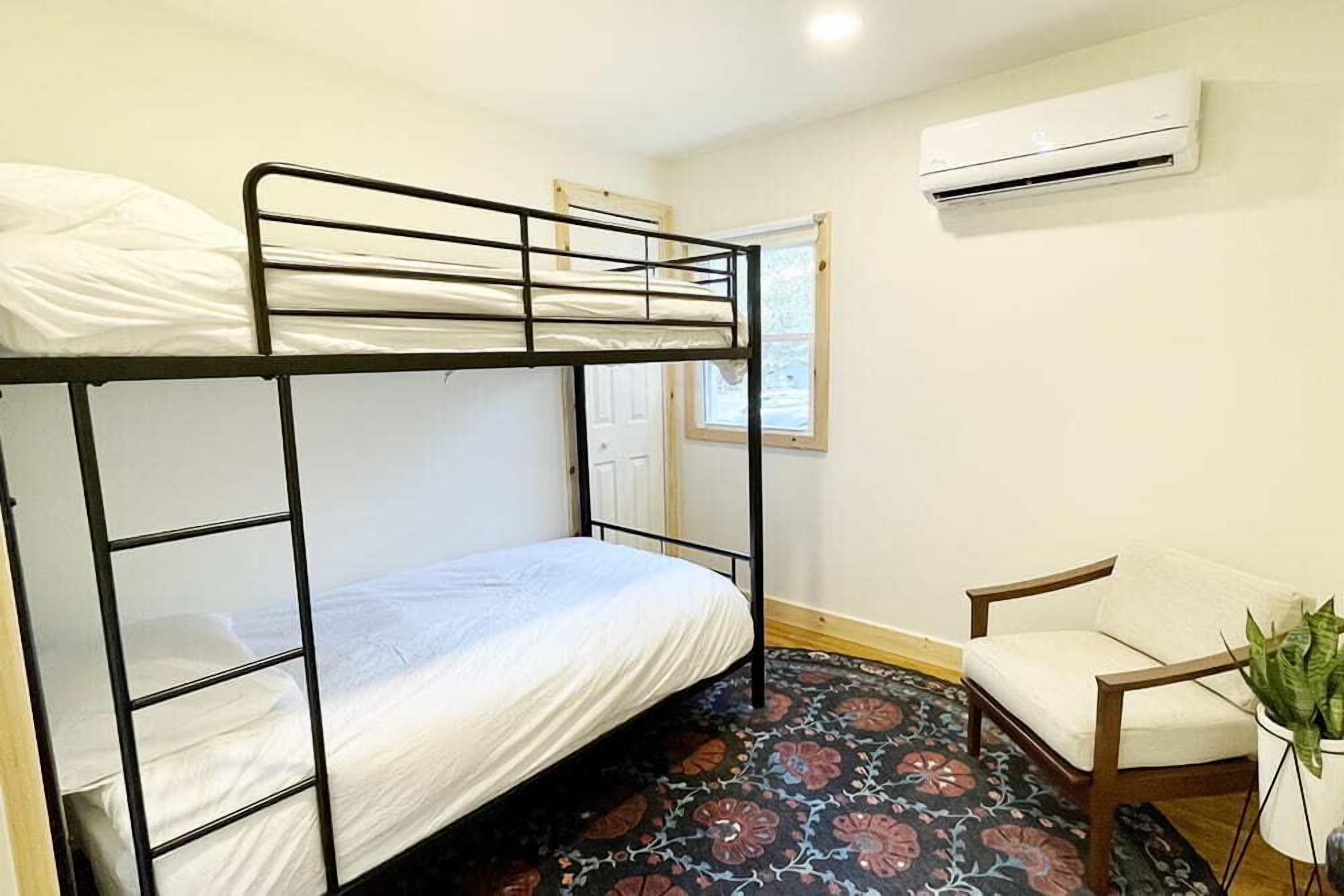 Habitación con literas, una silla y aire acondicionado.
