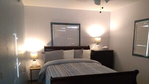 A bedroom with a bed, bedside lamps, a nightstand, a window with blinds, and a wall-mounted lamp. - Sleeping Ute Micro Suite in beautiful SW Colorado (Dolores)