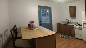 A compact kitchen with a wooden table, a chair, and a blue door. - Sleeping Ute Micro Suite in beautiful SW Colorado (Dolores)
