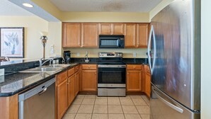 Una cocina con armarios de madera, un refrigerador de acero inoxidable, un microondas, un horno y un lavavajillas.