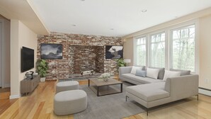 A modern living room with a brick wall, a large window, and a grey sofa. - New Luxury Listing: 5,000 sq/ft Secluded House (Weston)