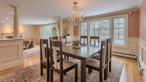 A dining room with a large table, six chairs, a chandelier, and large windows. - New Luxury Listing: 5,000 sq/ft Secluded House (Weston)