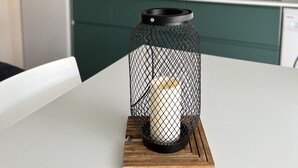 A modern kitchen with green cabinets, a white countertop, and a black wireframe lantern on a wooden coaster. - T2 apartment with garden near the beach (Valras-Plage)