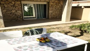 A table with a fruit bowl, a chair, and a stone wall in the background. - T2 apartment with garden near the beach (Valras-Plage)