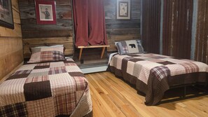 A cabin-style room with two beds, wooden walls, a small table, and a bench.