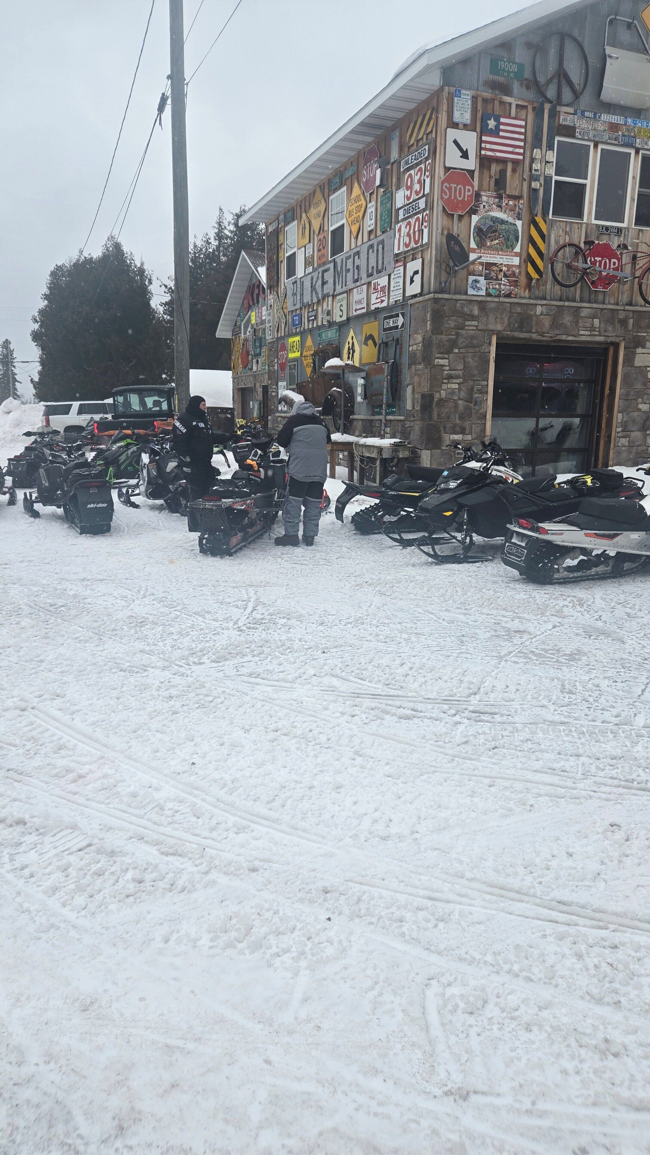A building with multiple signs and a row of snowmobiles parked outside.