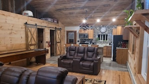 A cozy living room with leather recliners, a wooden bench, and a fireplace. - 3 Bedroom Loft With Game Room ~ In The Heart Of Downtown Copper Harbor (Copper Harbor)