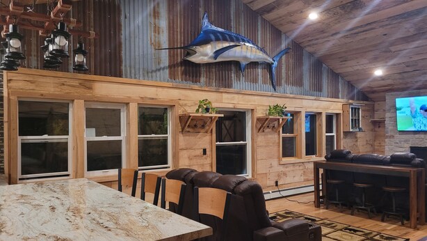 A rustic interior with wooden walls, a large fish mural, a bar area, and leather seating. - 3 Bedroom Loft With Game Room ~ In The Heart Of Downtown Copper Harbor (Copper Harbor)