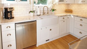 Een moderne keuken met witte kasten, een roestvrijstalen vaatwasser en een raam met uitzicht op groen.