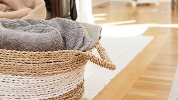 Une pièce chaleureuse avec un panier en osier, un tapis moelleux et une grande plante en pot.