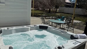 Un jacuzzi con una mesa y sillas en un patio trasero.