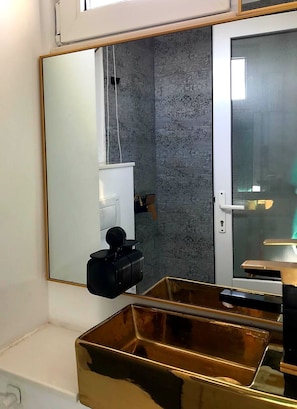 A bathroom with a large mirror, a shower, and a gold-colored storage unit. - Studio with Lake View (București)