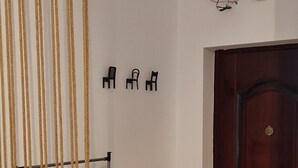A room with a wooden floor, a dark wooden door, a black metal rack with a yellow hanger, and a white wall with black chair icons. - Studio with Lake View (București)