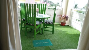 A small outdoor seating area with a round table and two green chairs with patterned cushions, a welcome mat, and a potted plant. - 1 Bedroom Penthouse Suite 63, Mystic Ridge Resort (Ocho Rios)