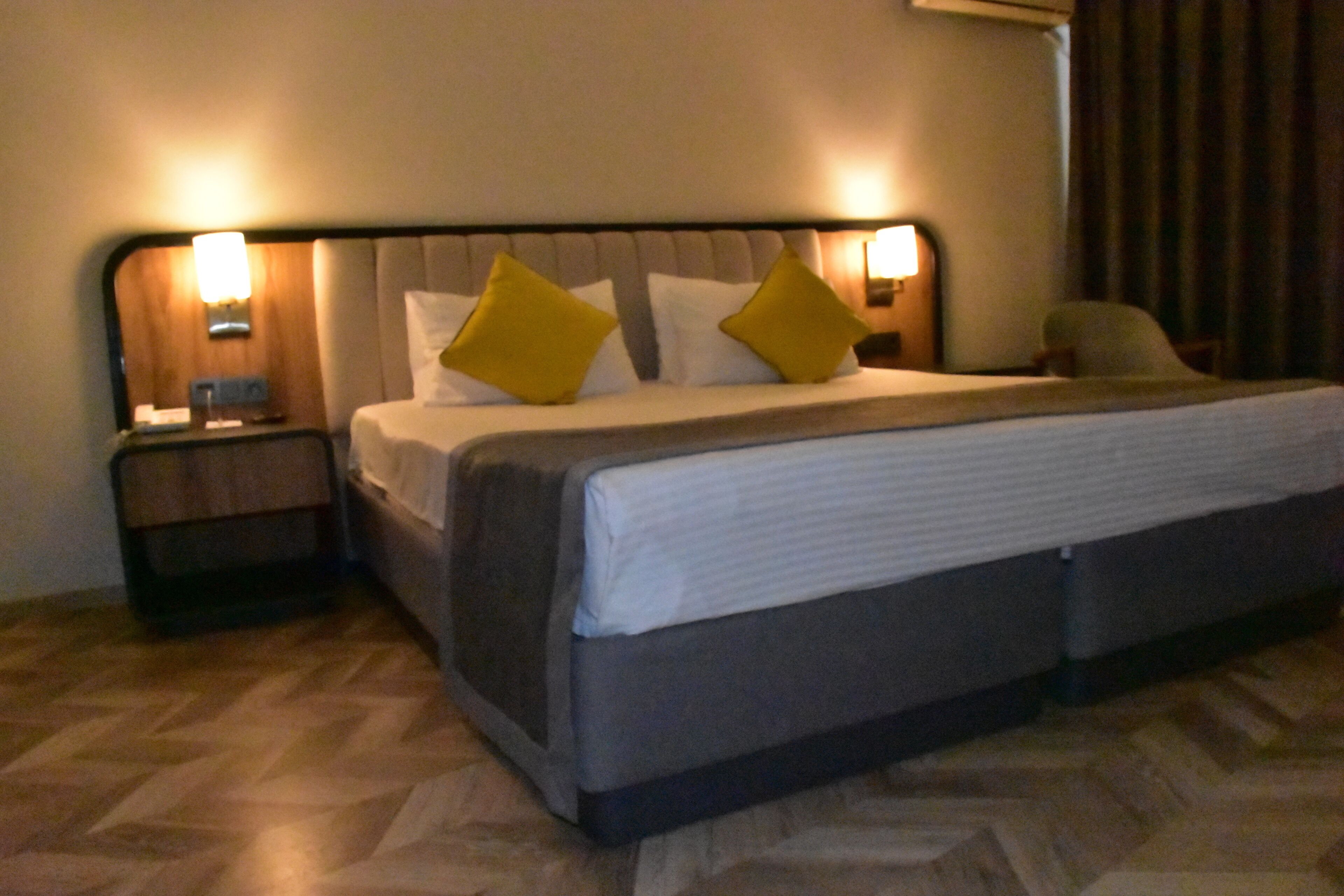 A hotel room with a bed, nightstands, and a wall-mounted lamp.