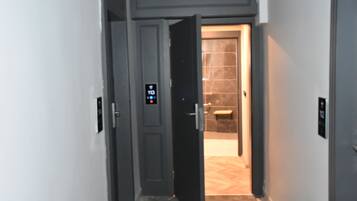Un pasillo con cerradura digital, zona de ducha y pared de azulejos.