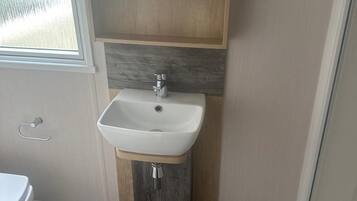Ein Badezimmer mit einem weißen Waschbecken, einem Holz-Waschtisch und einem Fenster.