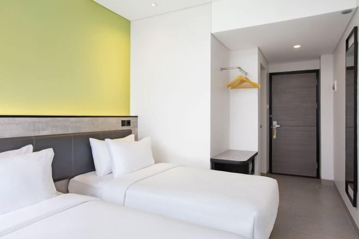 Ein Hotelzimmer mit zwei Betten, einem Nachttisch, einem Kleiderschrank und einer Tür.