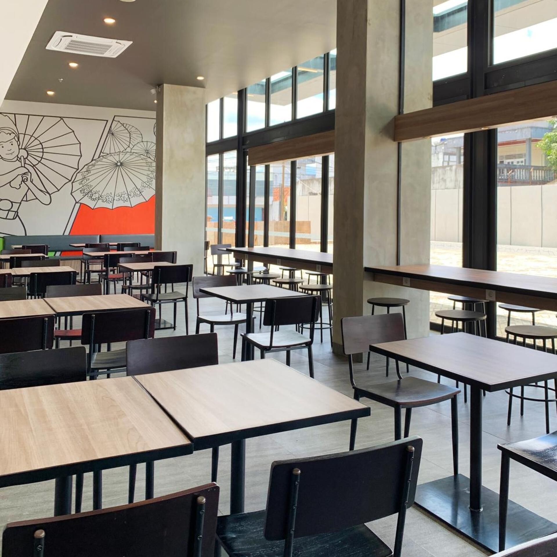 Un vaste espace intérieur aménagé en salle à manger, avec de hauts plafonds, de grandes fenêtres et un mobilier moderne.