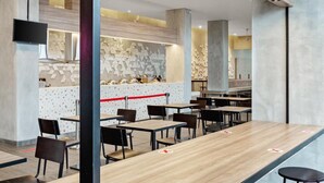 Ein modernes Restaurant mit langen Tischen, Stühlen und einer Theke.