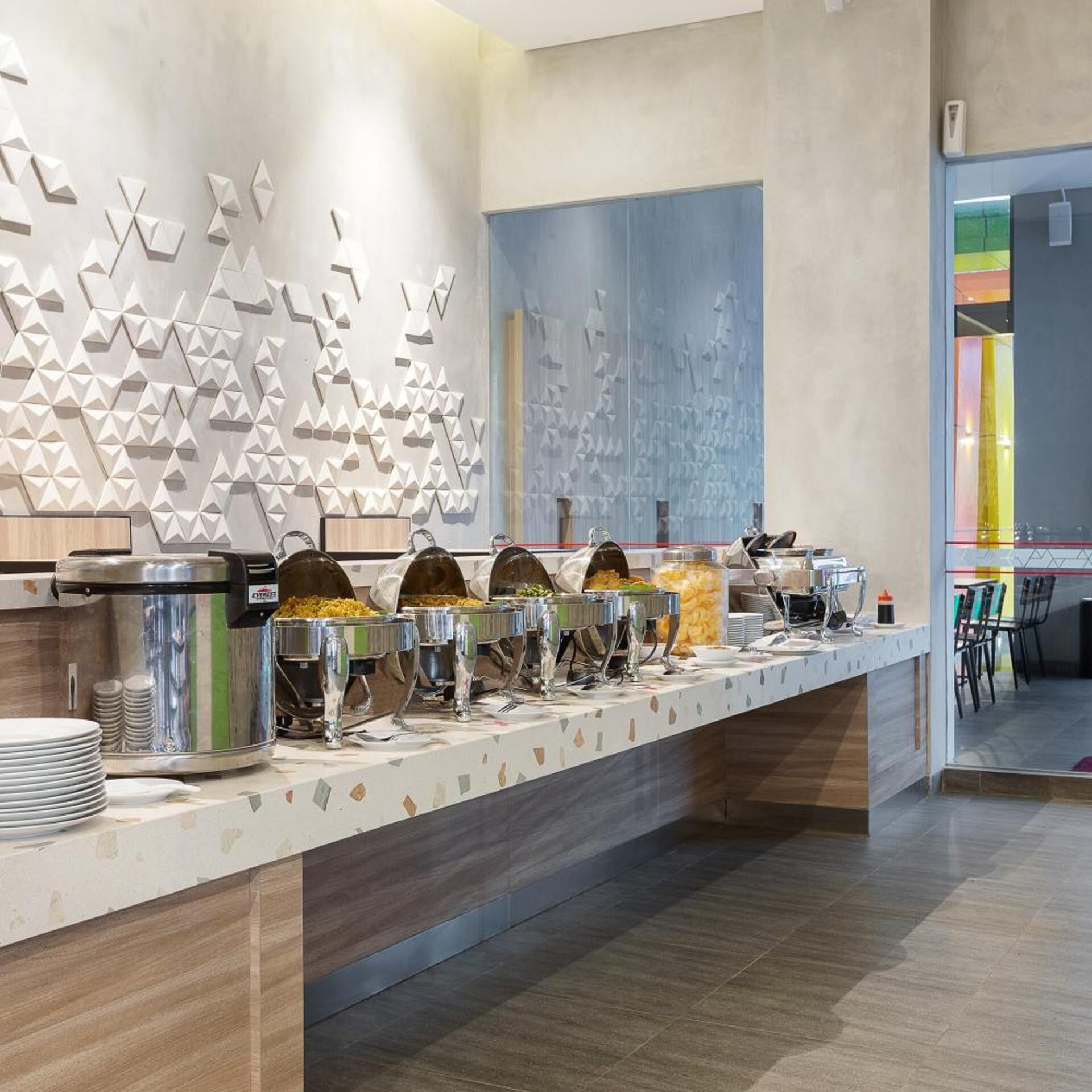 A buffet setup with multiple food containers and a modern wall design.