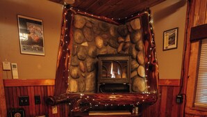 Una habitación acogedora con chimenea de piedra, estanterías de madera, cafetera y microondas.
