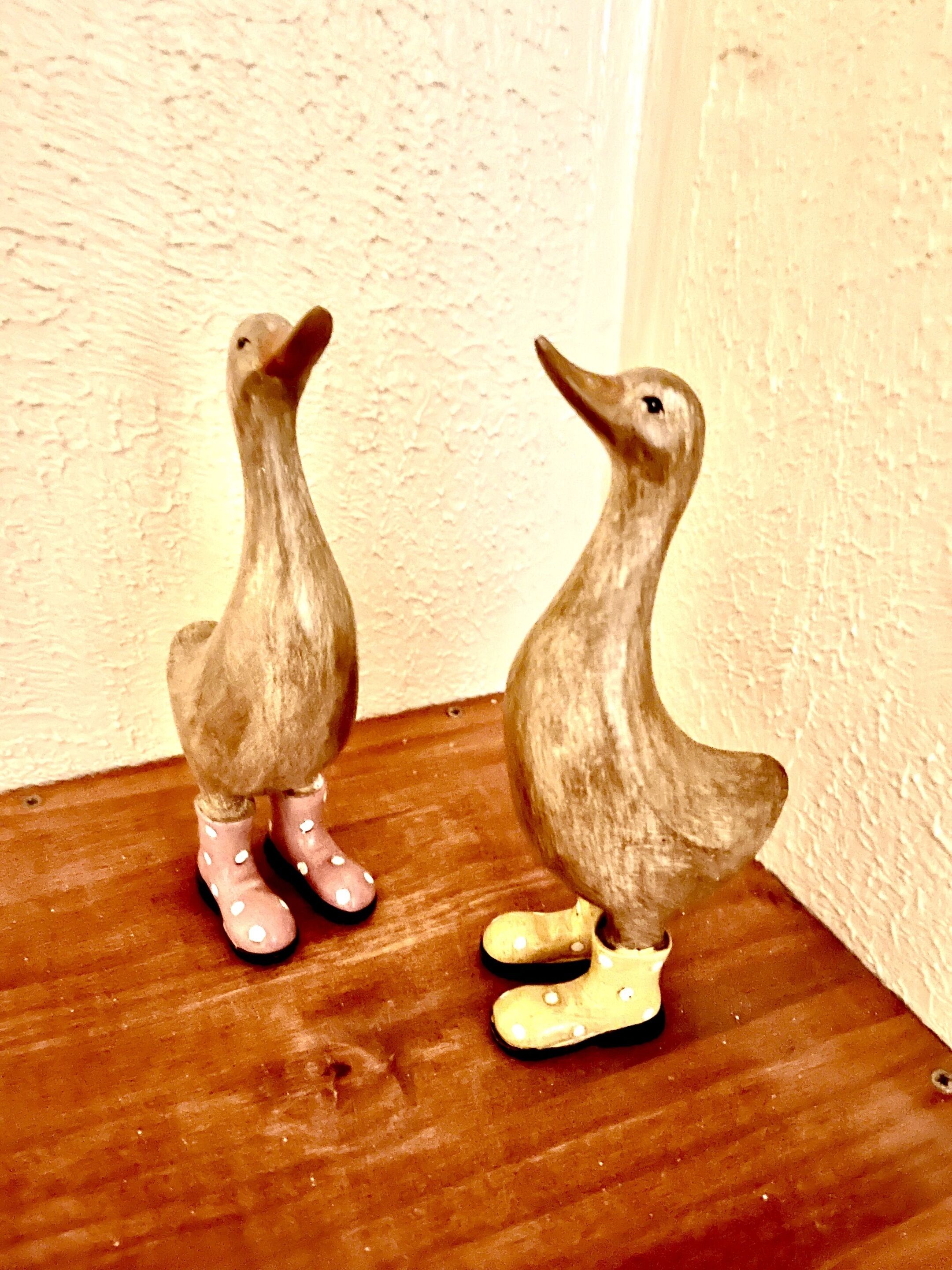 Twee keramieken eenden op een houten plank.