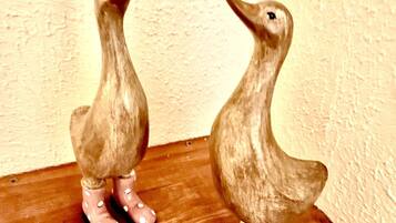 Twee keramieken eenden op een houten plank.