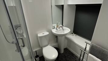 Une salle de bain moderne avec une douche à parois de verre, des toilettes, un lavabo et une baignoire.