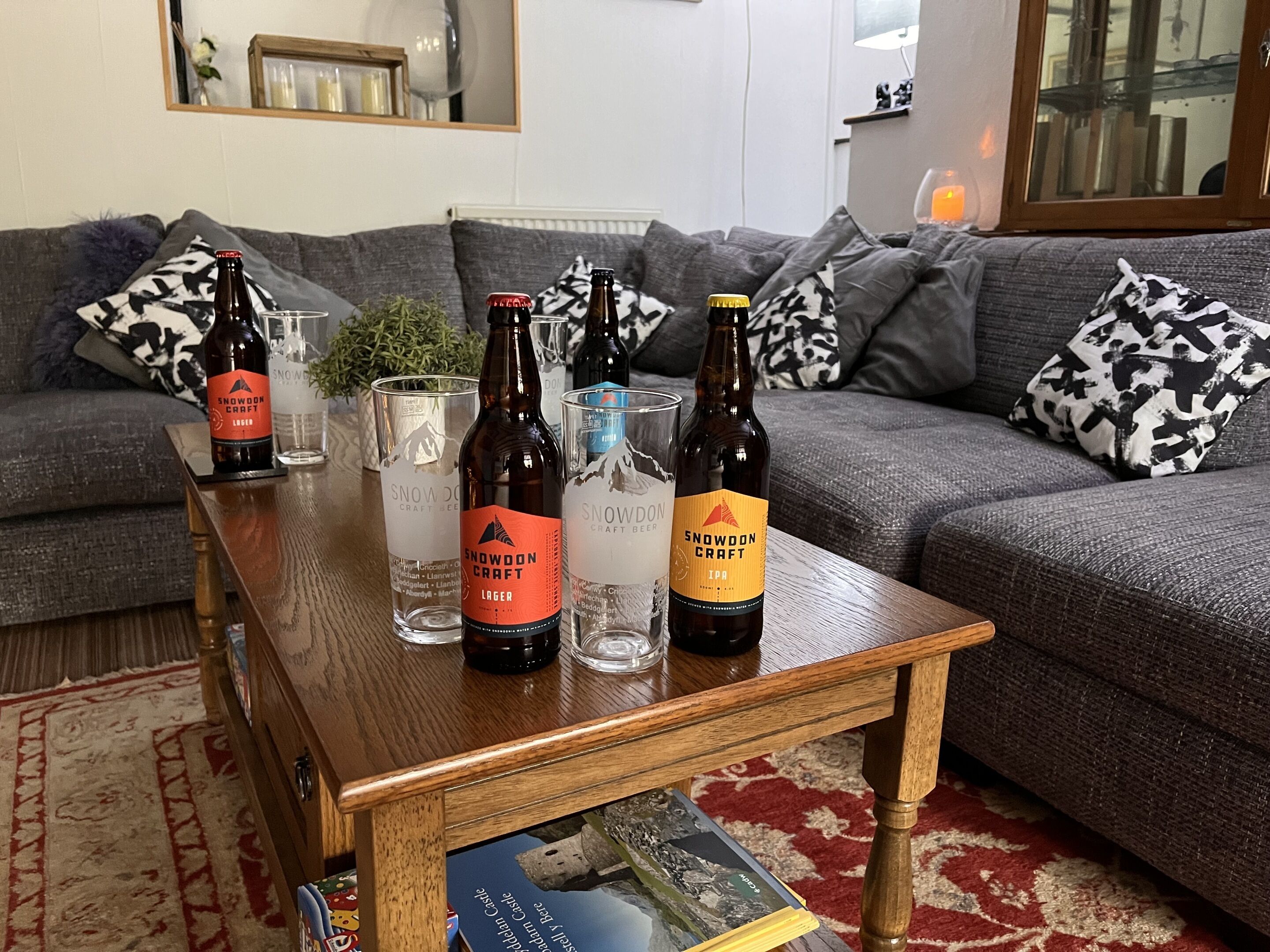 A living room with a coffee table holding several bottles of Snowdon Craft beer and glasses.