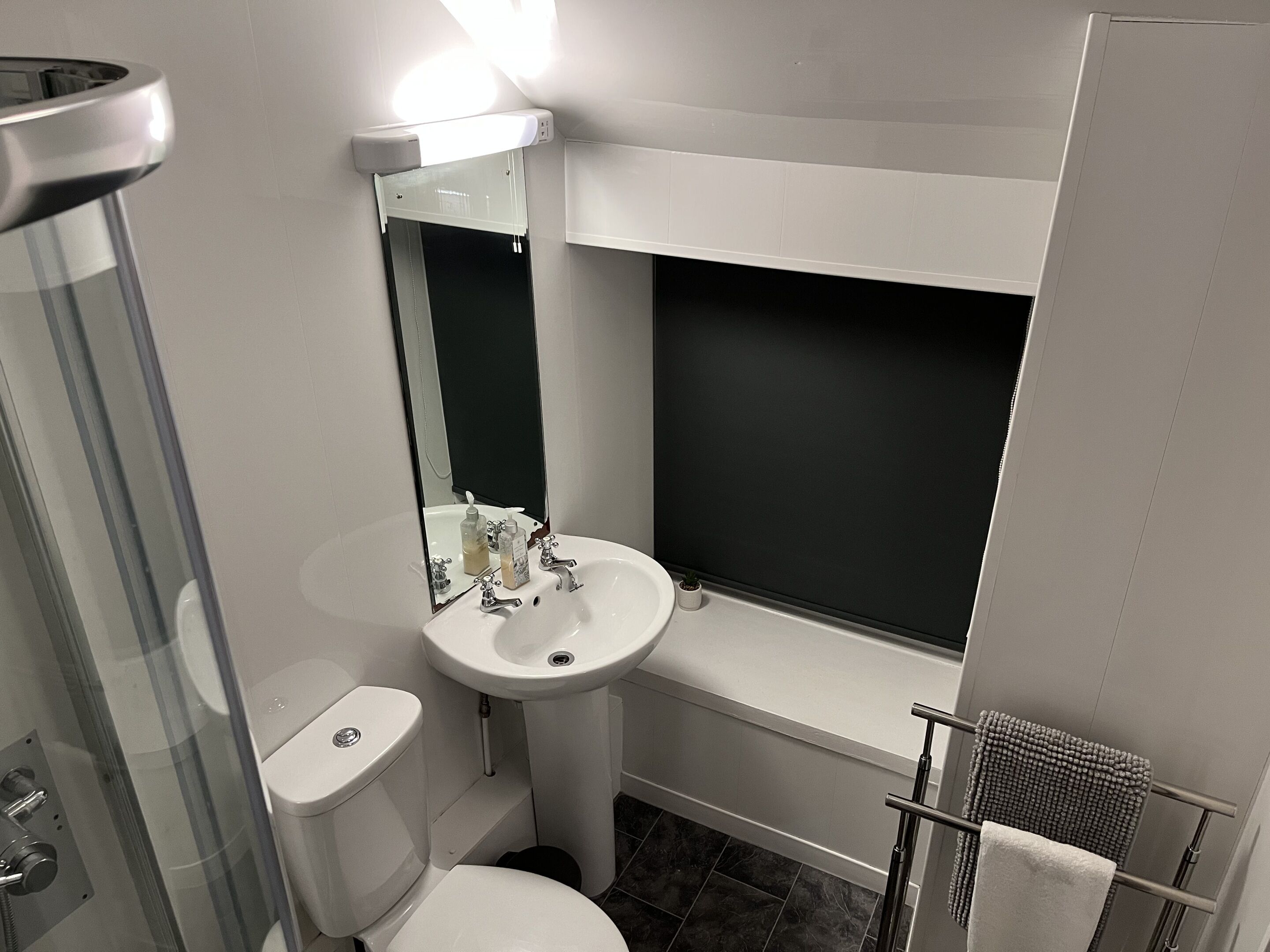 A compact bathroom with a white sink, mirror, and toilet.