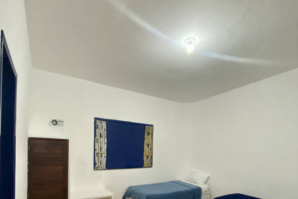 Ein Zimmer mit zwei Betten, einem Schreibtisch, einer Tür und einer Deckenleuchte.