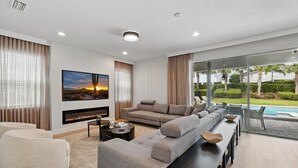 Un salon moderne avec un canapé d’angle, un téléviseur à écran plat et une cheminée.