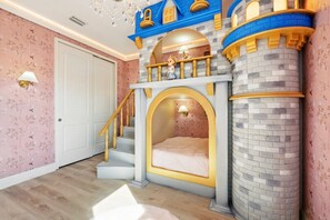 Un dormitorio con cama temática de castillo, una escalera y una puerta.