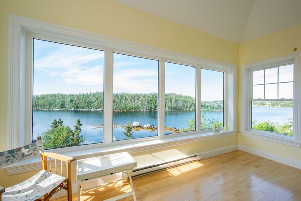 A room with large windows offering a view of a lake and forest. - Spacious villa by the sea (East Dover)