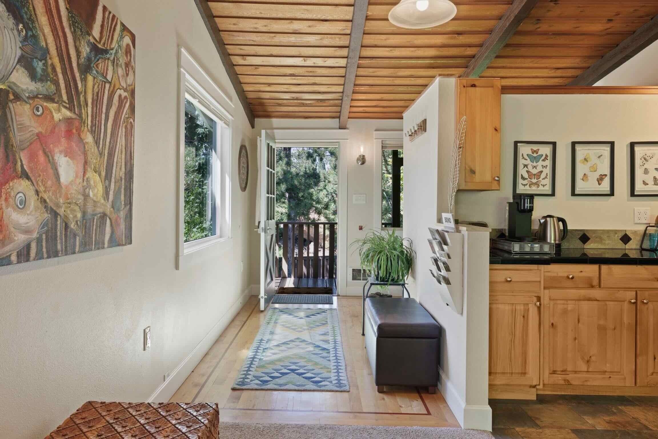 A kitchen with wooden cabinets, a black countertop, and a view of the outdoors.