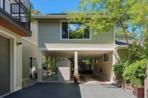 A two-story house with a covered porch, a garage, and a driveway. - Cozy Up at a Nature Inspired Boutique Studio in the Trees - River Nearby (Bend)