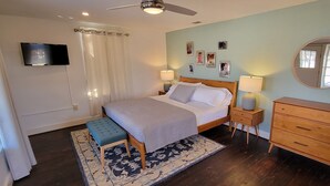 A bedroom with a bed, bedside tables, a dresser, a ceiling fan, a TV, and a large mirror. - Luxury Adobe Home near Marfa and McDonald Observatory (Fort Davis)