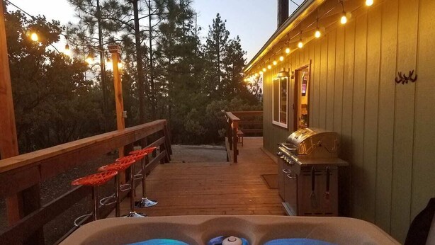 Eine Holzterrasse mit Whirlpool, Sitzgelegenheiten im Freien und Grillplatz.