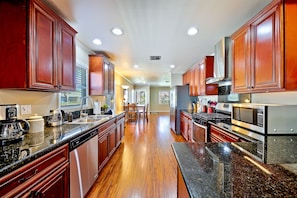 Enjoy cooking in this well-lit kitchen with sleek cabinetry, granite countertop, and stainless steel appliances.